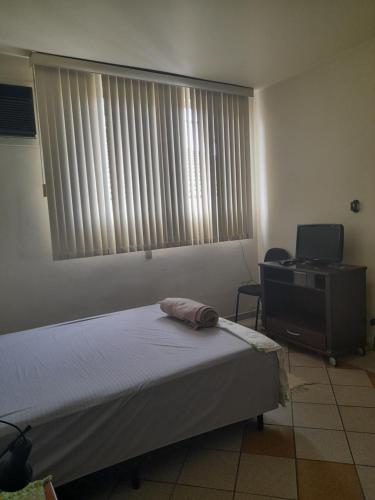 a bedroom with a bed and a desk and a window at 4 suítes privativas in Santos