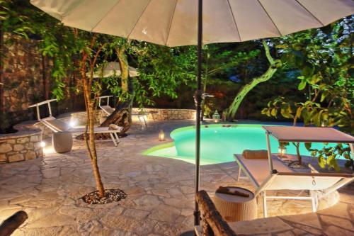 an umbrella and chairs next to a swimming pool at Kitrini Luxury Cottage in Zenempisátika