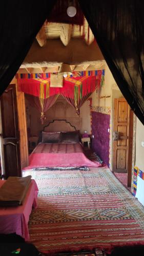 - une chambre avec un grand lit à baldaquin dans l'établissement Kasbah Maktob Tamnougalt, à Agdz