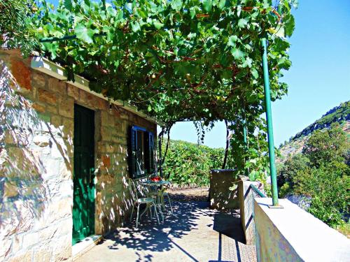 a building with a table and chairs under a tree at House Sv. Lovre in Postira