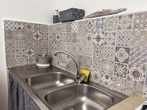 um lavatório de aço inoxidável numa cozinha com azulejos em Camping Flintstones Park em Cava dʼAliga