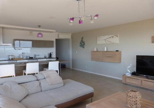 un salon avec un canapé et une cuisine dans l'établissement La Perle Marine, Luxe et Raffinement, appartement T4 Front de mer, à Narbonne