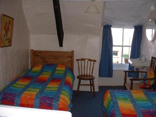1 dormitorio con 1 cama, 1 silla y 1 ventana en Dolphin Cottage 50m from Shaldon Beach! en Shaldon