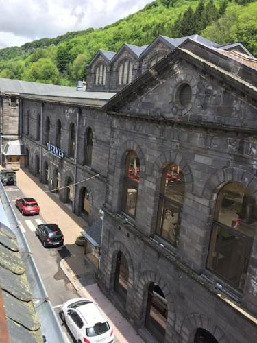 - un grand bâtiment en pierre avec des voitures garées devant dans l'établissement Studio face au Thermes, à Le Mont-Dore