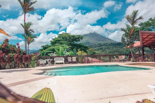 a swimming pool with a mountain in the background at Miradas Arenal Hotel & Hotsprings in Fortuna