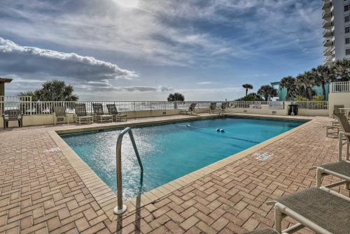 a swimming pool with chairs and the ocean in the background at Oceanfront Ormond Beach Condo - Steps to Shore! in Ormond Beach