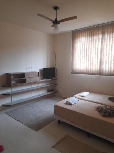 a white room with two beds and a television at 4 suítes privativas in Santos