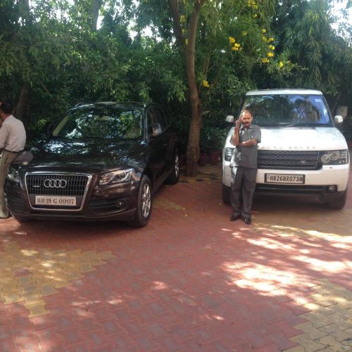 a man taking a picture of a black car and a white van at The Radha Ashok in Mathura
