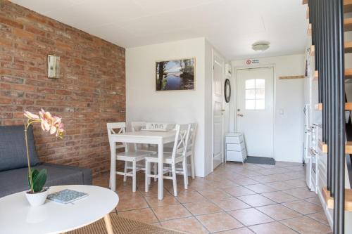 a living room with a table and chairs and a brick wall at Lilla Paradiset in Tomelilla