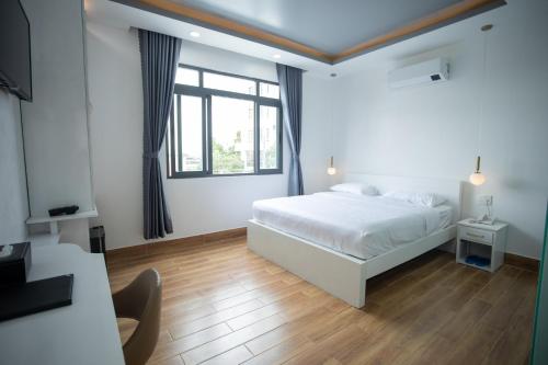 a white bedroom with a bed and a window at AOC HOTEL in Cao Lãnh