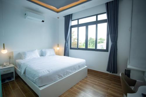 a bedroom with a white bed and a window at AOC HOTEL in Cao Lãnh