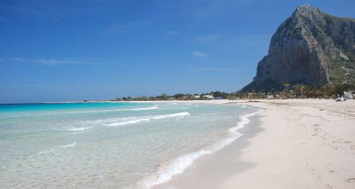 une plage avec l'océan et une montagne en arrière-plan dans l'établissement AFFITTACAMERE A TRE MINUTI IN SPIAGGIA Il Veliero, à San Vito Lo Capo