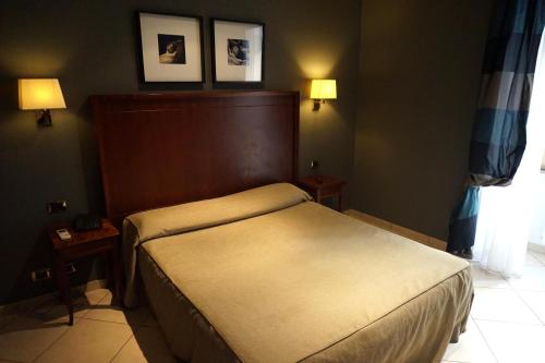 a bedroom with a bed and two pictures on the wall at Hotel Taormina in Rome