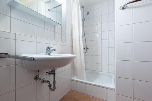 y baño blanco con lavabo y bañera. en Ferienwohnpark Immenstaad am Bodensee Ein-Zimmer-Apartment 55 11 en Immenstaad am Bodensee