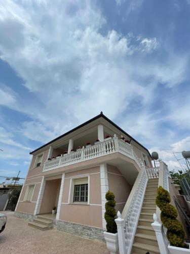 a pink house with a white balcony and stairs at Rent rooms Loren in Vlorë