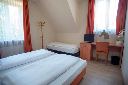 um quarto com 2 camas e uma secretária com um computador em Albergo Cavallino s'Rössl em Merano