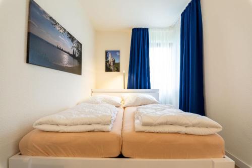 - une chambre avec un lit doté de rideaux bleus dans l'établissement Ferienwohnpark Immenstaad am Bodensee Ein-Zimmer-Apartment 55 17, à Immenstaad am Bodensee