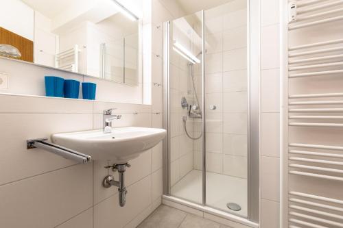 La salle de bains est pourvue d'un lavabo et d'une douche. dans l'établissement Ferienwohnpark Immenstaad am Bodensee Ein-Zimmer-Apartment 55 17, à Immenstaad am Bodensee