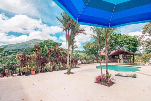 a resort with a swimming pool and a blue umbrella at Miradas Arenal Hotel & Hotsprings in Fortuna
