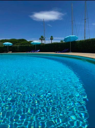 une piscine bleue avec des parasols bleus en arrière-plan dans l'établissement Mon Ecrin sur la marina du Golfe de St Tropez, à Cogolin
