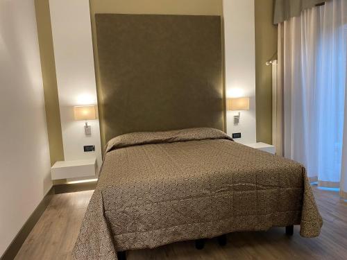 a bedroom with a bed and two lamps and a window at Hotel Giulietta Romeo in Lazise