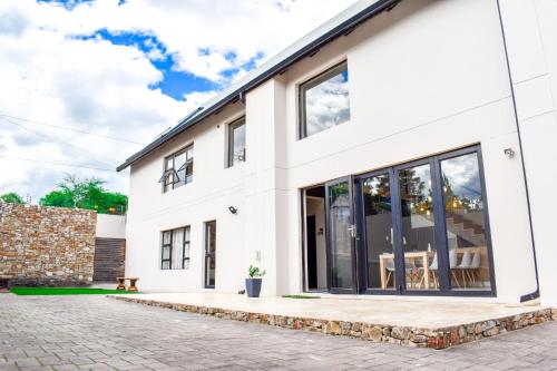 a white house with large windows and a patio at Amabwe Guesthouse in Grahamstown