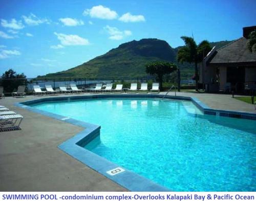 una gran piscina azul con sillas y una montaña en Banyan Harbor, en Lihue