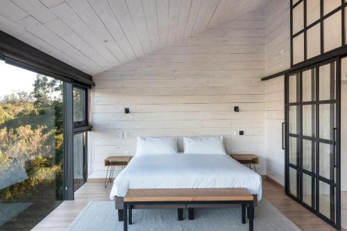 a bedroom in a house with a bed and windows at Cabañas Foráneo in Puerto Varas