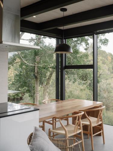 a dining room with a wooden table and a large window at Cabañas Foráneo in Puerto Varas
