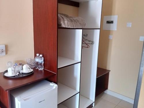 a room with a white closet with a shelf at Impovu Guest House in Kasane