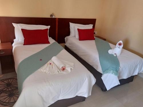 two beds in a hotel room with towels on them at Impovu Guest House in Kasane