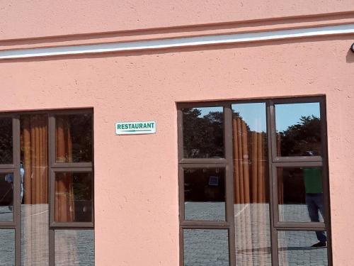 a sign on the side of a pink building with windows at Impovu Guest House in Kasane