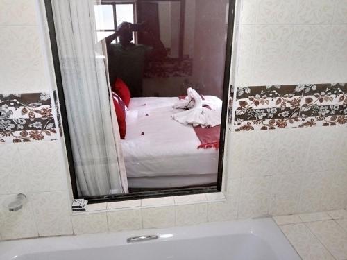 a bathroom mirror with a bed in the reflection of it at Impovu Guest House in Kasane