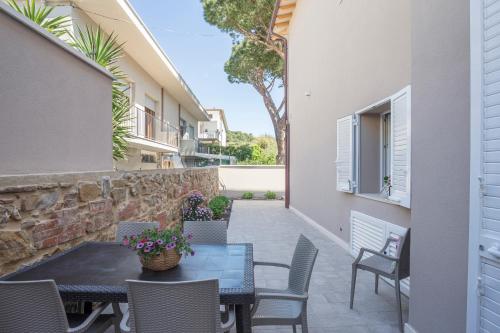 a patio with a table and chairs and a stone wall at Prima dell'Elba Family Apartments in Piombino