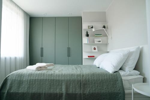 a bedroom with a bed with a green bedspread at Grey Green Cozy Apartment in Birštonas