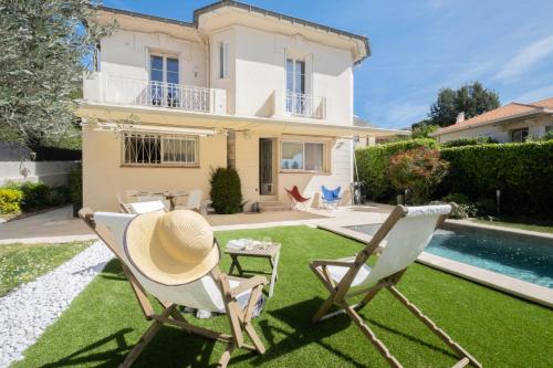 un chapeau et des chaises sur la pelouse devant une maison dans l'établissement COUP DE COEUR  Maison pour 8 avec piscine à 5 pieds du centre de Cannes, à Cannes