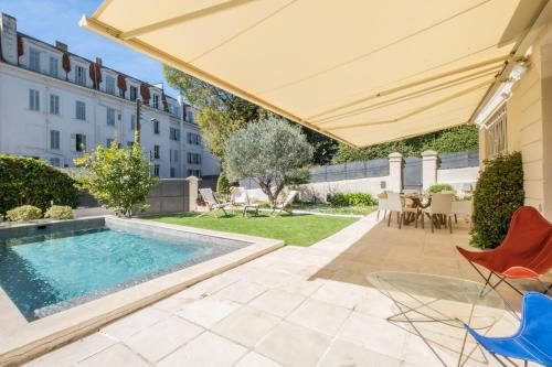 une terrasse avec une piscine, des chaises et un parasol dans l'établissement COUP DE COEUR  Maison pour 8 avec piscine à 5 pieds du centre de Cannes, à Cannes
