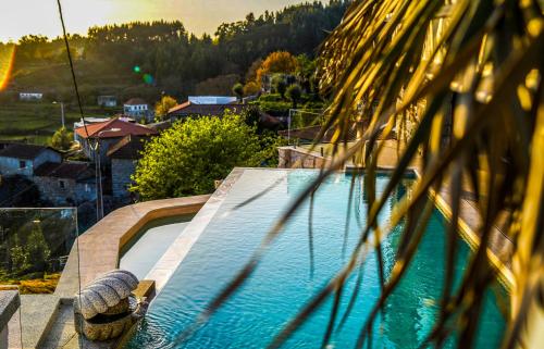 a swimming pool with a palm tree in the foreground at Quinta da Nascente in Soutelo