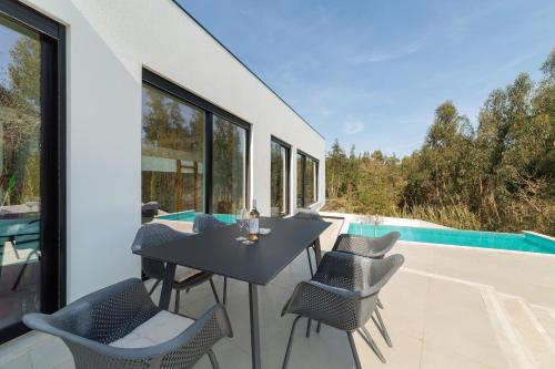 a patio with a table and chairs next to a pool at Villa Floresta - By SCH in São Martinho do Porto
