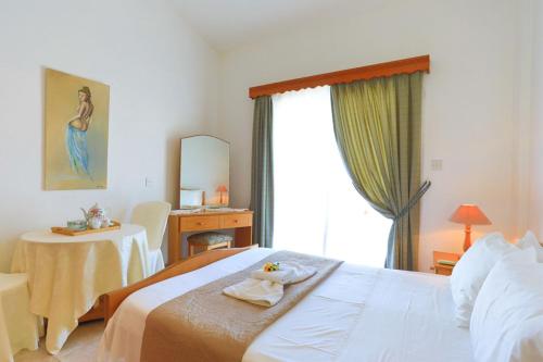 Schlafzimmer mit einem Bett, einem Tisch und einem Fenster in der Unterkunft Lemon Grove Villa Dio in Argaka