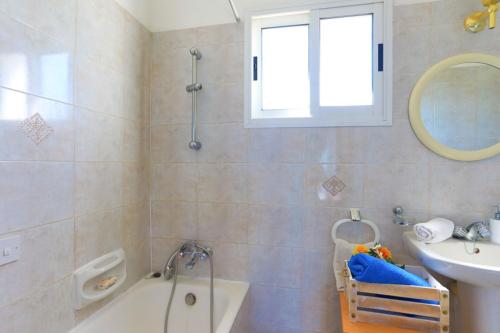 a bathroom with a bath tub and a sink and a mirror at Lemon Grove Villa Dio in Argaka