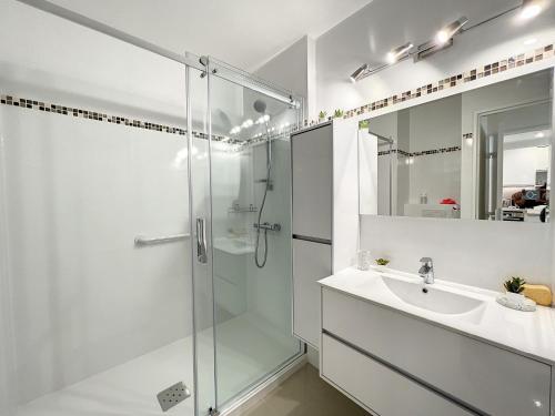 a white bathroom with a shower and a sink at VILLA MAUPASSANT T2 BORD DE MER in Cannes
