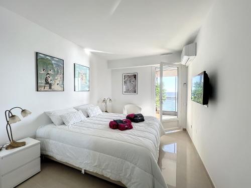 Un dormitorio blanco con una cama grande con dos bolsas. en VILLA MAUPASSANT T2 BORD DE MER en Cannes