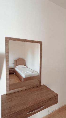 a mirror reflecting a bed in a room at Hotel Nino in Dhërmi