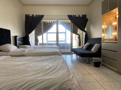 a bedroom with two beds and a chair and a window at درة العروس - القرية الحالمة - شقة دور أرضي على البحر - Dream Village in Durat Alarous