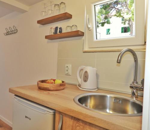 a kitchen with a sink and a bowl of fruit on a counter at Apartmani Robert in Bol