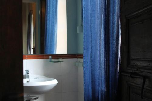 a bathroom with a sink and a blue shower curtain at Room and Breakfast Torre in Felino