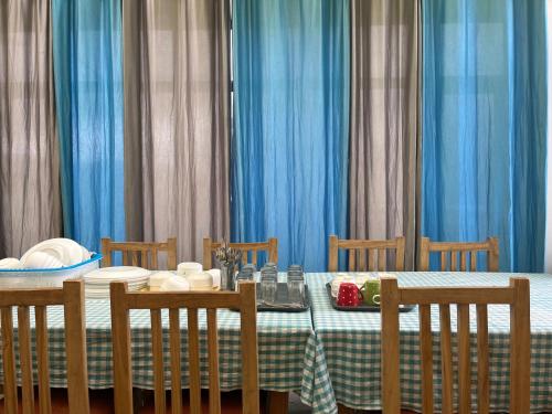 a dining table with blue curtains and a table with chairs at The Puma house in Leh