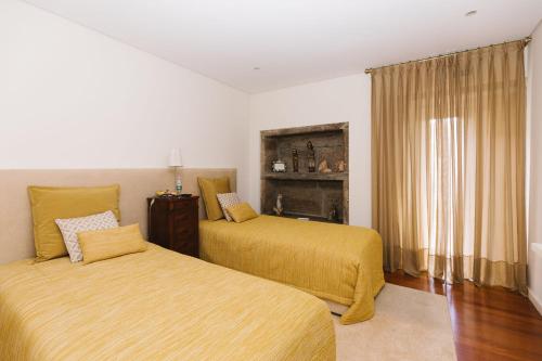 a bedroom with two beds with yellow sheets and a window at Casa do Passadiço - Alvarenga in Alvarenga