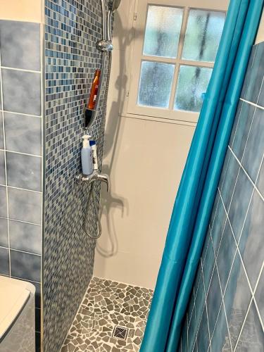 La salle de bains est pourvue d'une douche et d'un mur carrelé bleu. dans l'établissement Rez-de Villa Piscine, à Cavalaire-sur-Mer
